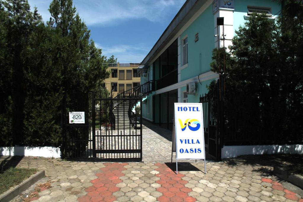 a sign in front of a building with a gate at Hotel Villa Oasis in Kobuleti