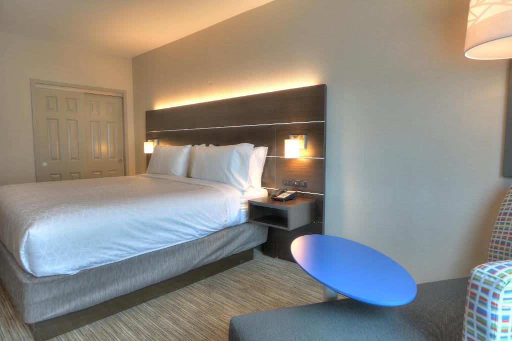 a hotel room with a bed and a blue table at Holiday Inn Express Hotel & Suites Mobile Saraland by IHG in Saraland