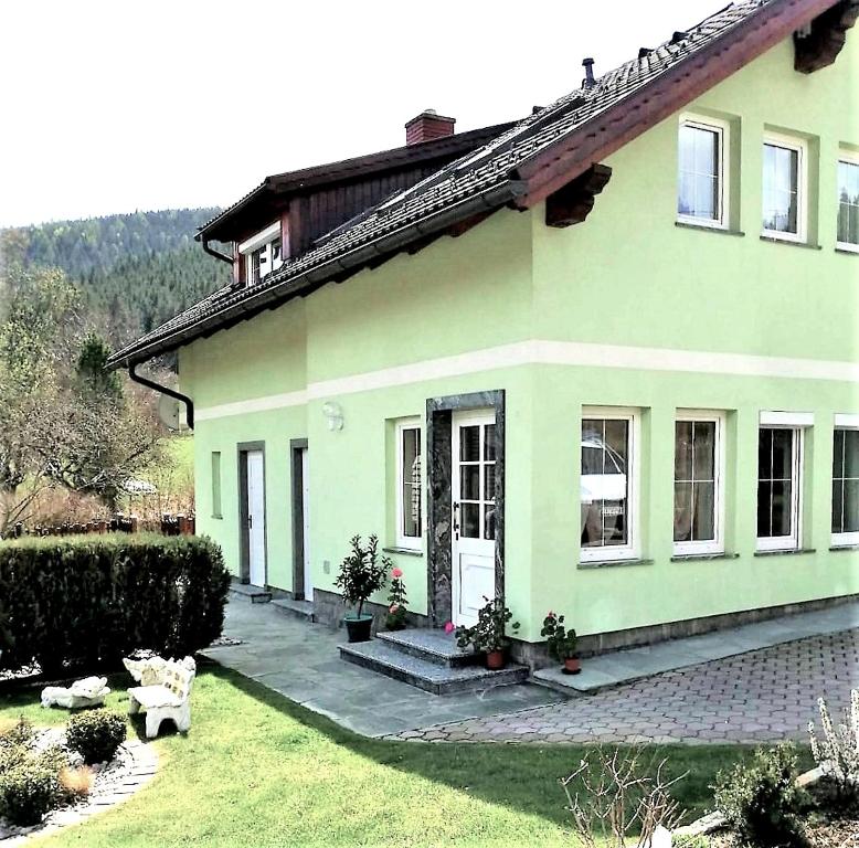 ein grünes Haus mit einer weißen Tür im Hof in der Unterkunft Ferienhaus Familie Lagler in Glödnitz