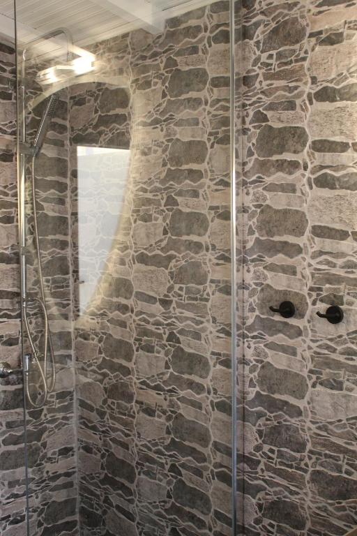 a bathroom with a glass shower with a stone wall at Cycladic Villa in Amorgos Island (Maison Shiro) in Arkesíni