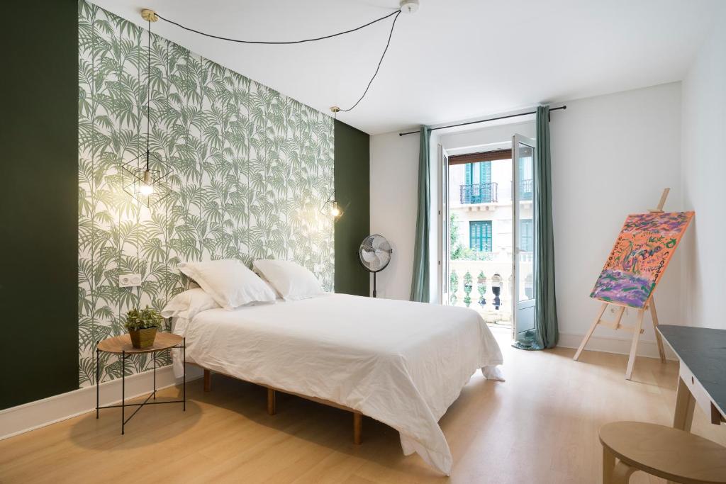 1 dormitorio con cama blanca y pared verde en Usandizaga Apartment, Second line beach, free Parking, en San Sebastián