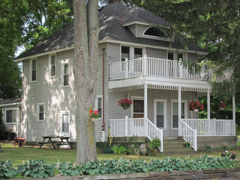 a white house with a porch and a tree at Devil's Lake Inn and Devil's Lake Inn Too in Manitou Beach