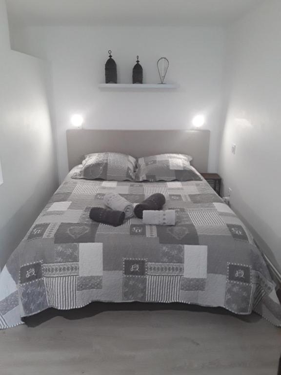 een slaapkamer met een bed met een deken en kussens bij Gîte les Oliviers les HERBIERS in Les Herbiers