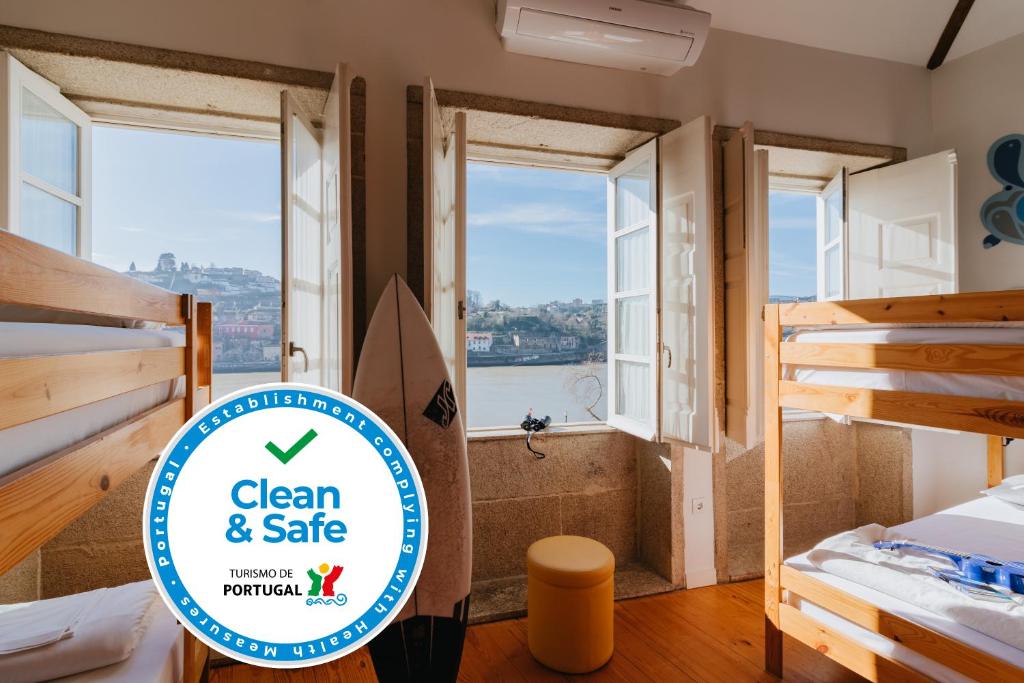 a room with a bed and a window with a view of the ocean at Happy Porto Hostel & Apartments in Porto