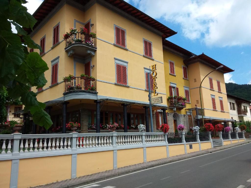 a yellow building with red windows and balconies on a street at Hotel La Rosa in Ronta
