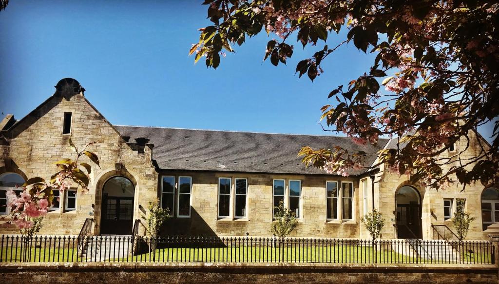 金羅斯的住宿－The Old Schoolhouse, Kinross，一座古老的砖砌建筑,前面有栅栏