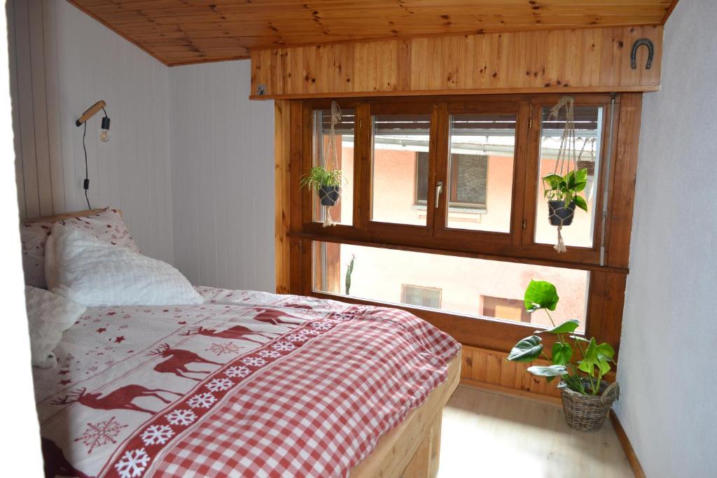 a bedroom with a bed and a window with potted plants at Chez Cathy chambre chez l'habitante in Bremis