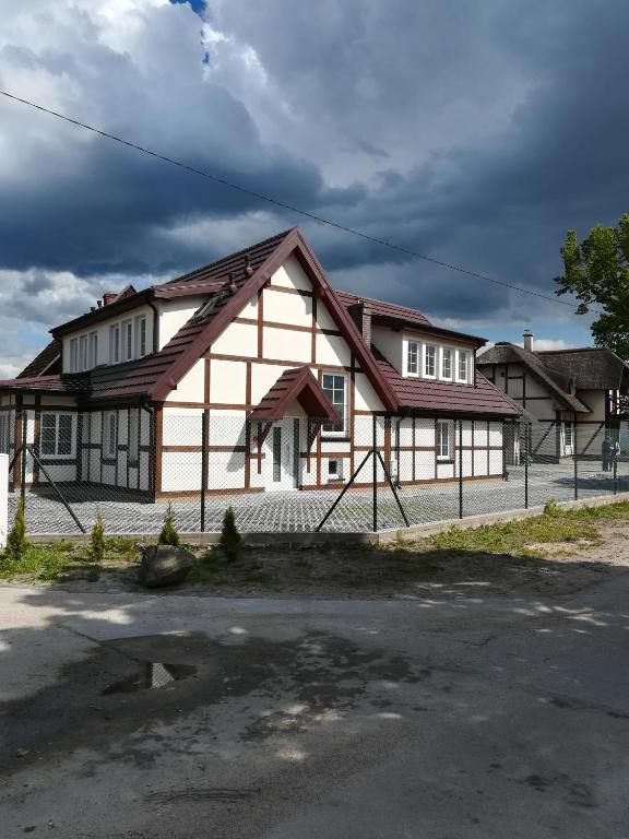 ein weiß-braunes Haus mit einem Zaun in der Unterkunft Armona in Ustka
