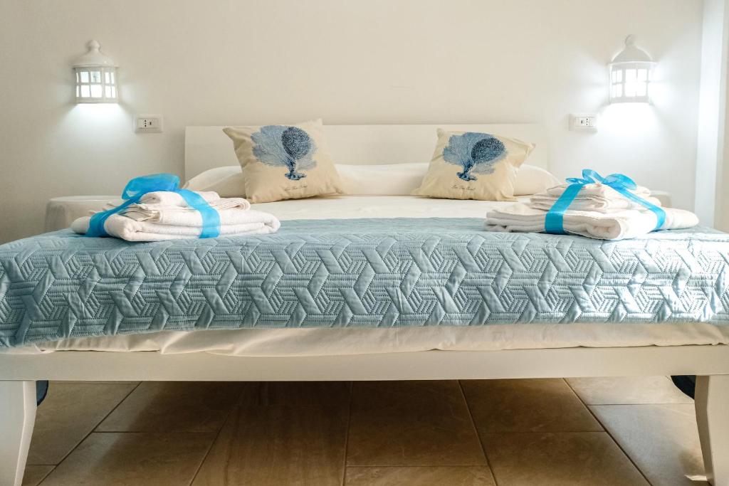 Una cama blanca con toallas azules y blancas. en Tenuta L'Alba di monte Matino, en Otranto
