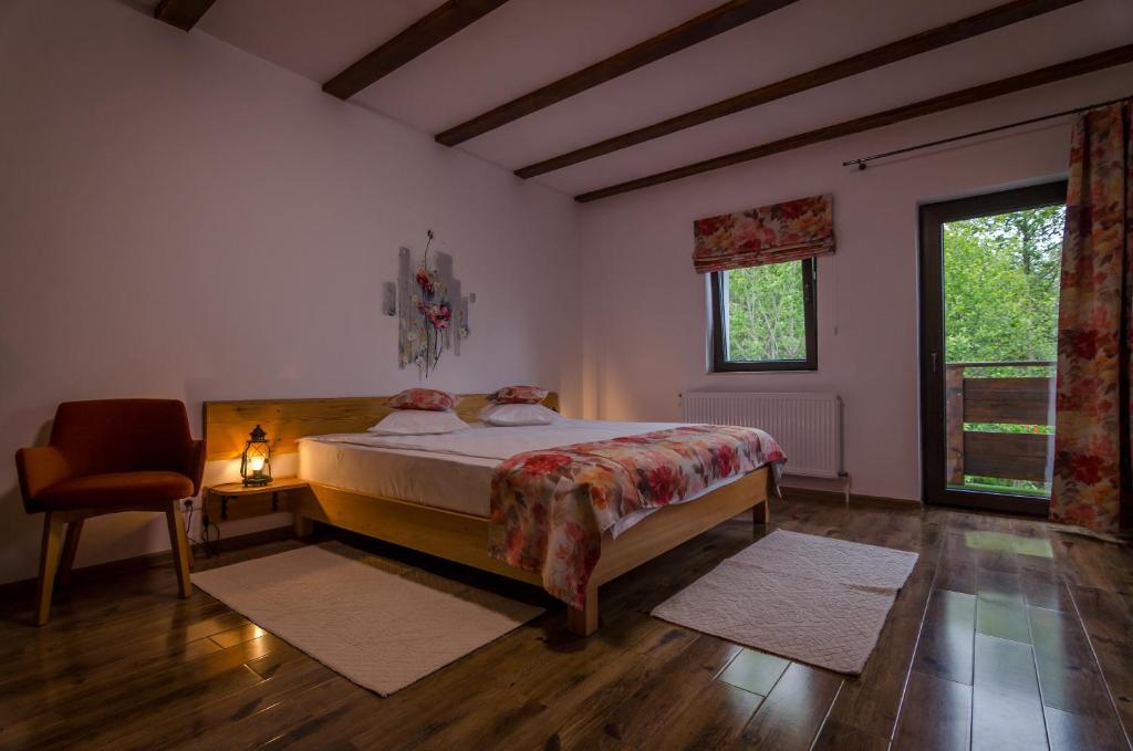 a bedroom with a bed and a chair and a window at Acasa la Mariuca in Bran