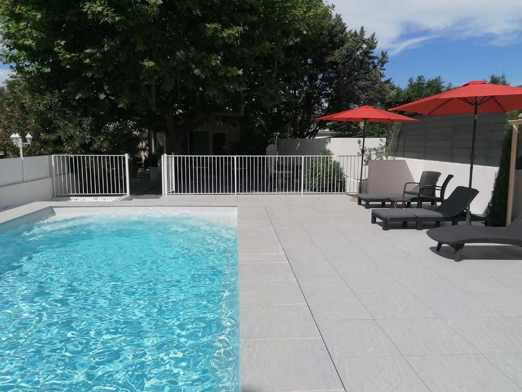 a swimming pool with two chairs and two umbrellas at Logis Le Printemps Hôtel Restaurant - Montélimar in Montélimar