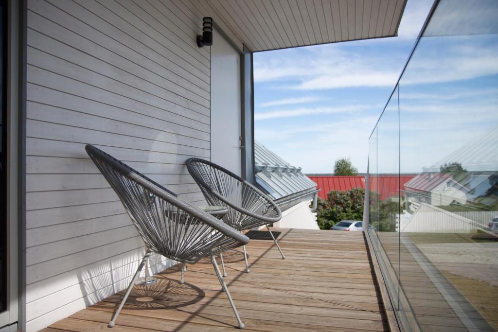 2 chaises assises sur la terrasse couverte d'une maison dans l'établissement Käsmu Holiday House, à Käsmu