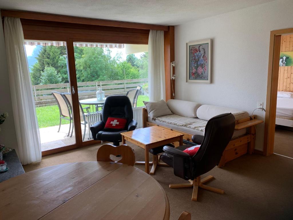 uma sala de estar com um sofá, cadeiras e uma mesa em Roc d'Orsay E52 em Leysin