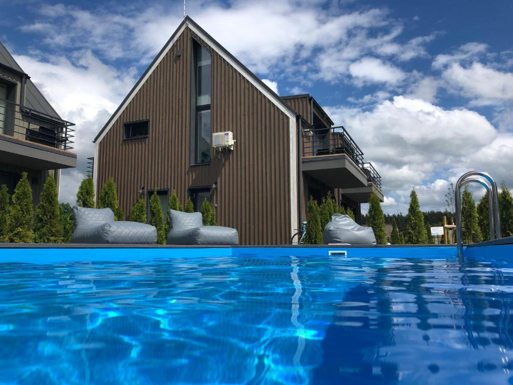 a house with a swimming pool in front of a building at Rainbow Palanga in Palanga
