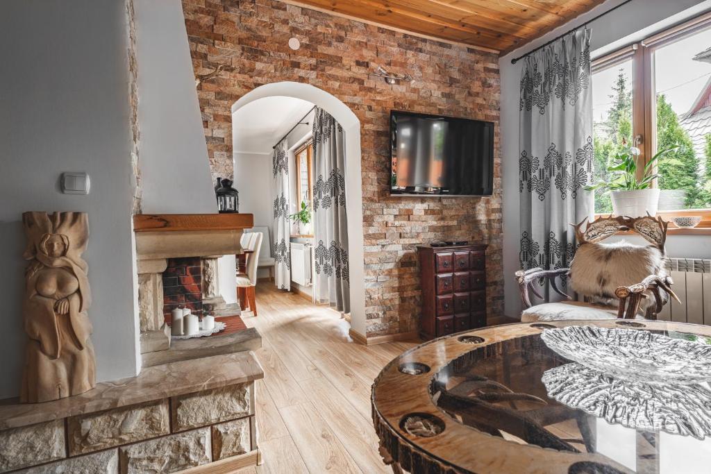 una sala de estar con una pared de ladrillo y una mesa en Domki pod Strzechą, en Zakopane