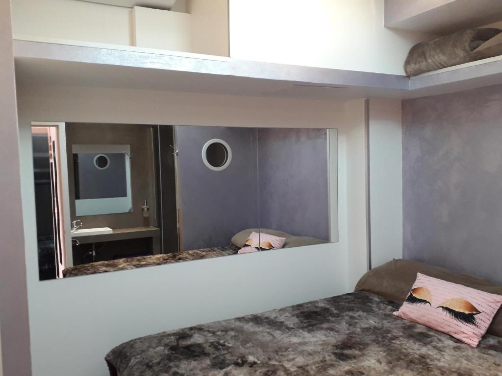 una camera da letto con specchio e letto di Chambres d'Hotes NATURISTE, Village Naturiste Cap d'Agde, Draps, Serviette, Café, Menage inclus en fin de sejour a Cap d'Agde