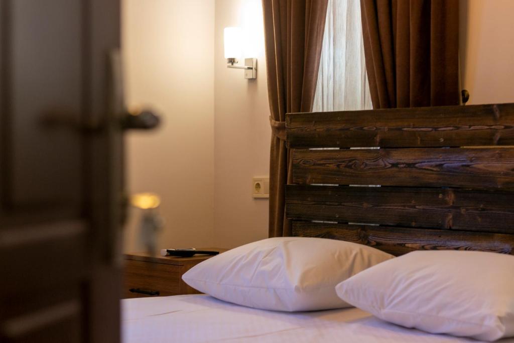 a bed with white pillows and a wooden headboard at Pera Boutique Hotel in Antalya