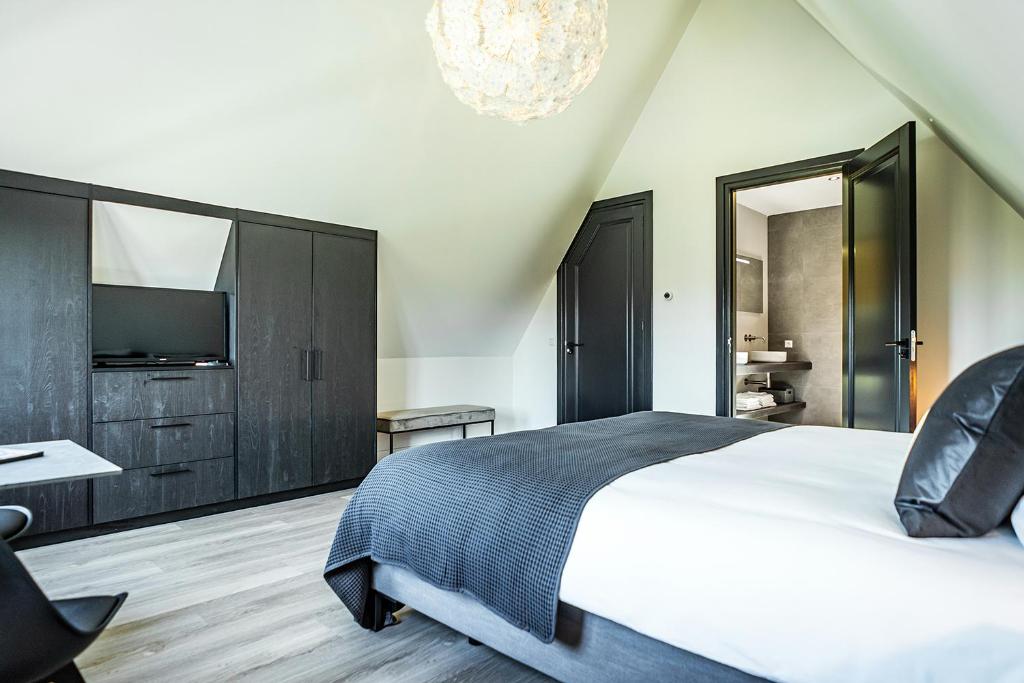 1 dormitorio con 1 cama grande y TV en Het Vergulde Visje, en Den Burg