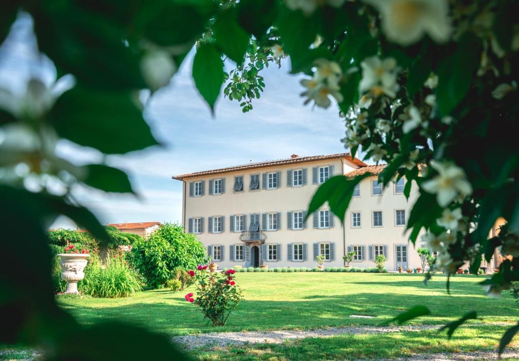 a large white building on a grass field at Villa La Preziosa in Lucca