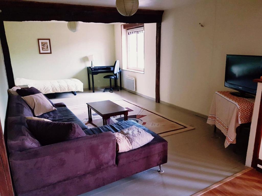 a living room with a couch and a piano at Gîte cosy 4 à 9 personnes in Buffières