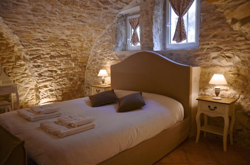 a bedroom with a bed with two tables and two windows at LOCUS AMOENUS in Lirac