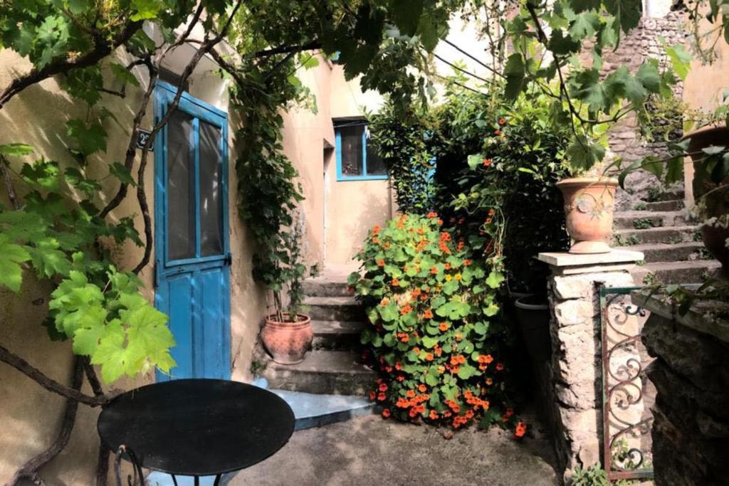 une entrée à une maison avec une porte bleue et quelques fleurs dans l'établissement Charmante maison de village à Fontaine-de-Vaucluse, à Fontaine-de-Vaucluse