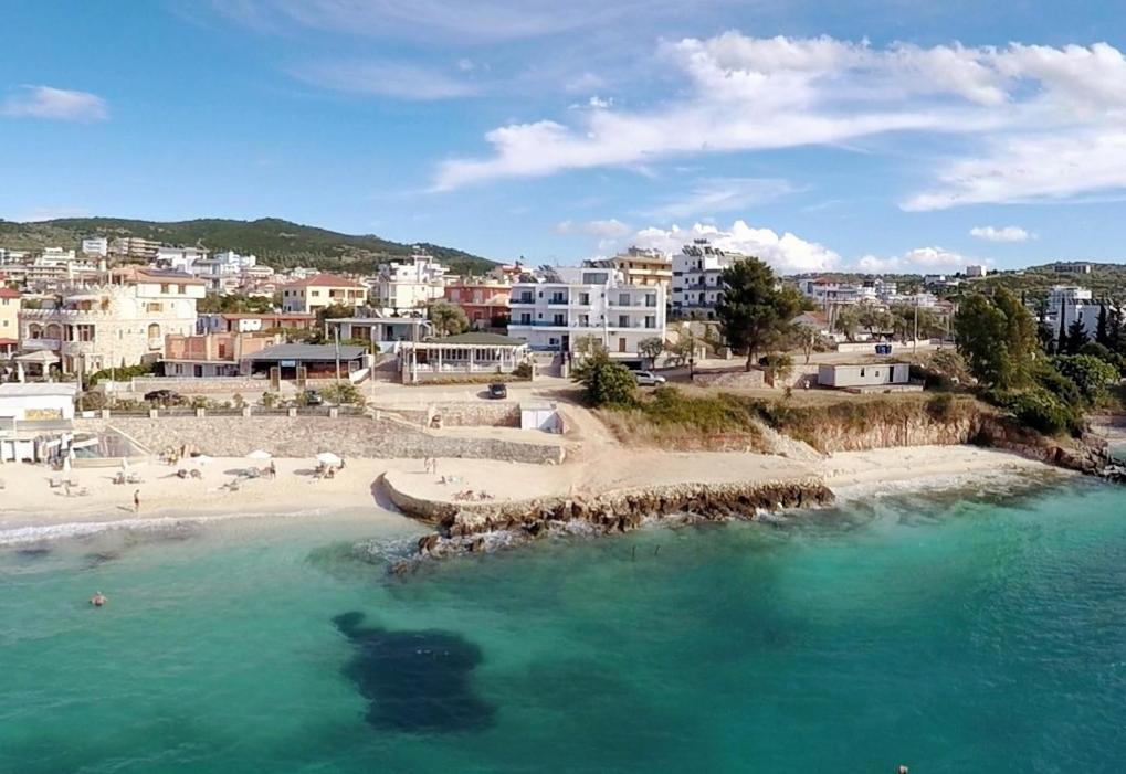 Blick auf einen Strand mit Gebäuden im Hintergrund in der Unterkunft Hotel De Luna in Ksamil