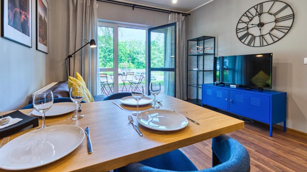 una sala da pranzo con tavolo, sedie e orologio di Apartament Nastrojowy-Holiday Mountain Residence - 5D Apartamenty a Świeradów-Zdrój