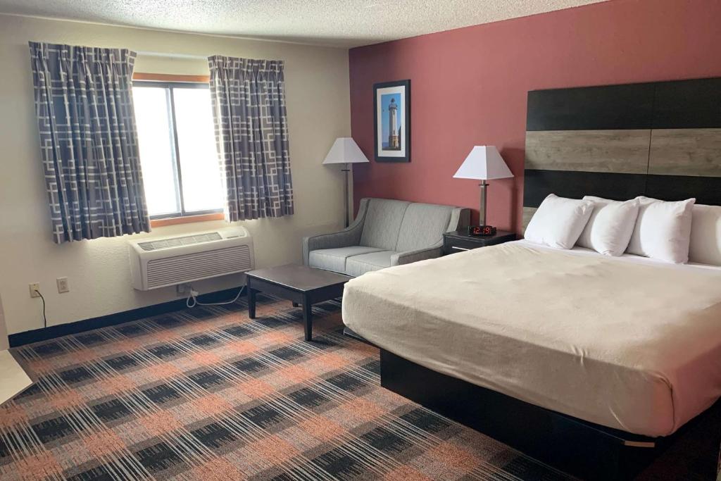 Habitación de hotel con cama y silla en Baymont by Wyndham Waupun, en Waupun