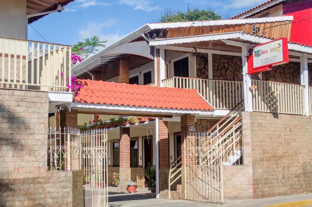 een bakstenen gebouw met een oranje dak en een hek bij Pousada Beira Rio in Santo Antônio do Pinhal