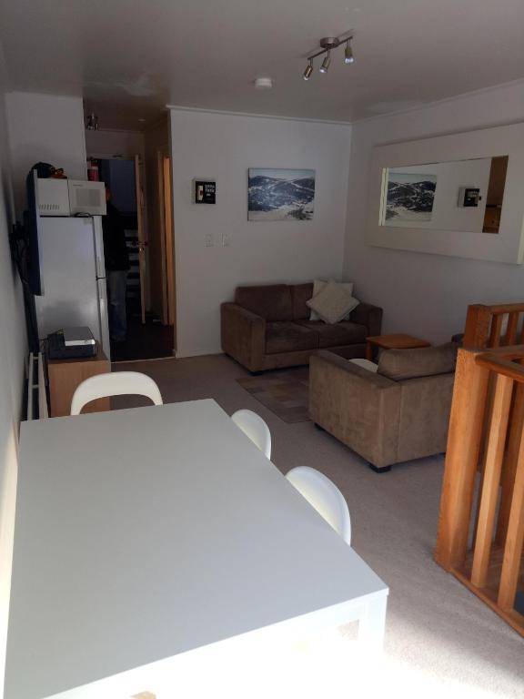 a living room with a couch and a table and chairs at Shamrock Apartment 5 in Mount Hotham