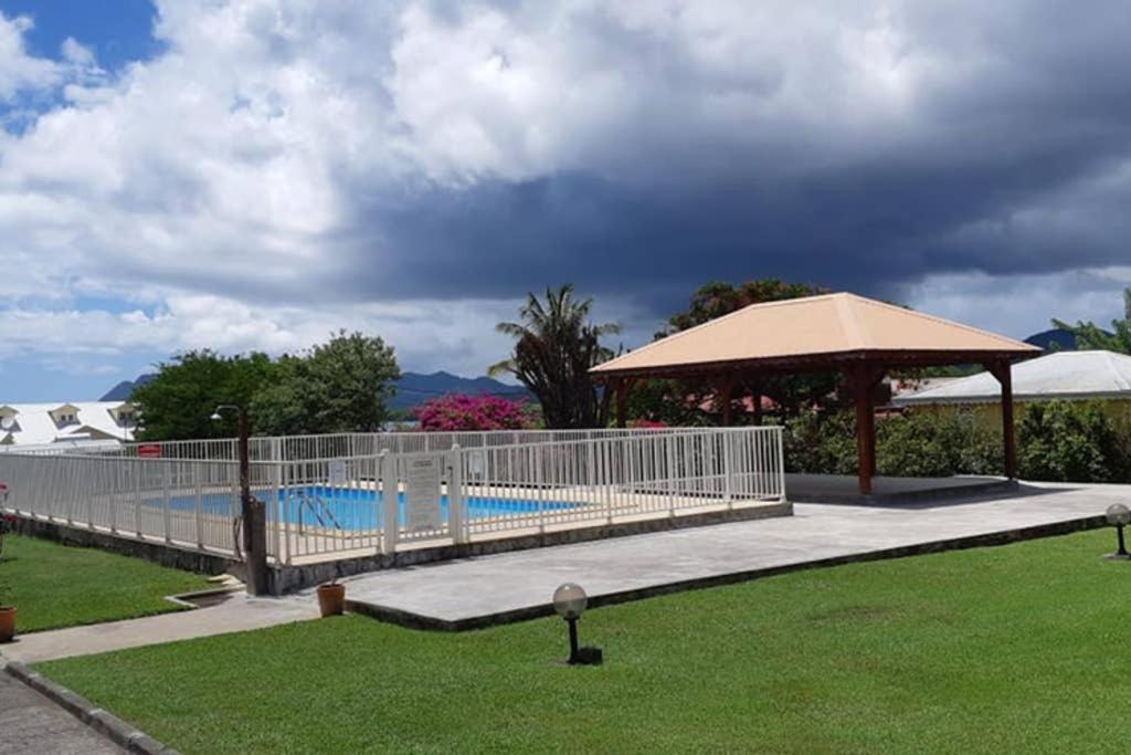 a fence around a swimming pool with an umbrella at Sweety Bounty in Sainte-Luce