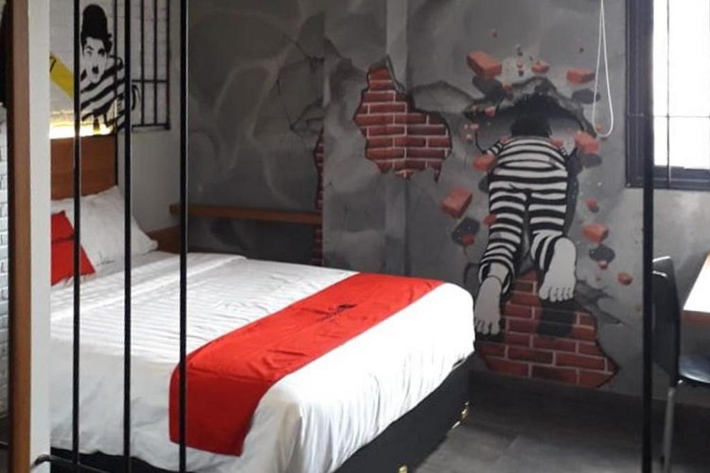 RedDoorz Plus @ Doorman Guest House في باندونغ: غرفة نوم مع سرير مع هيكل عظمي على الحائط