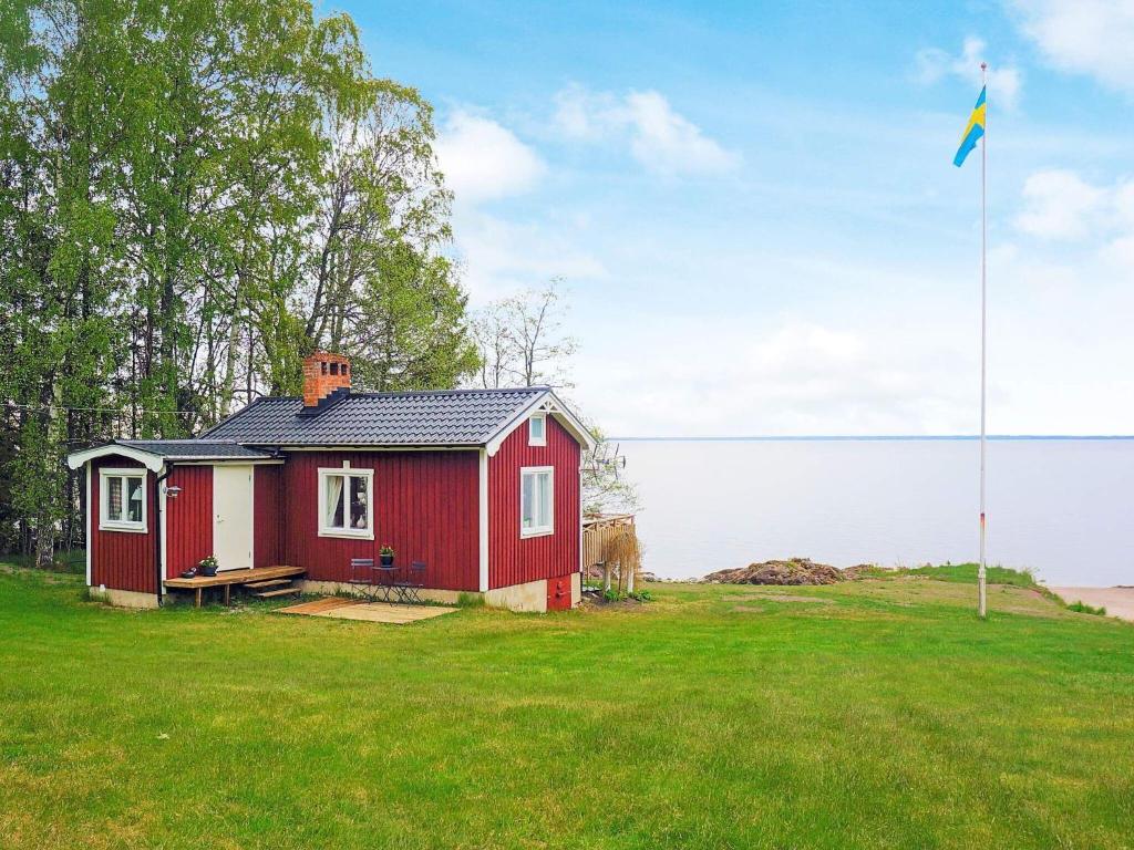 ein kleines rotes Haus auf einem Feld mit Flagge in der Unterkunft 2 person holiday home in FR NDEFORS in Frändefors