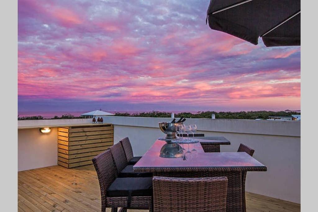 d'une table et de chaises sur un balcon avec vue sur le coucher du soleil. dans l'établissement Top-floor beachside apartment with views, à Casuarina