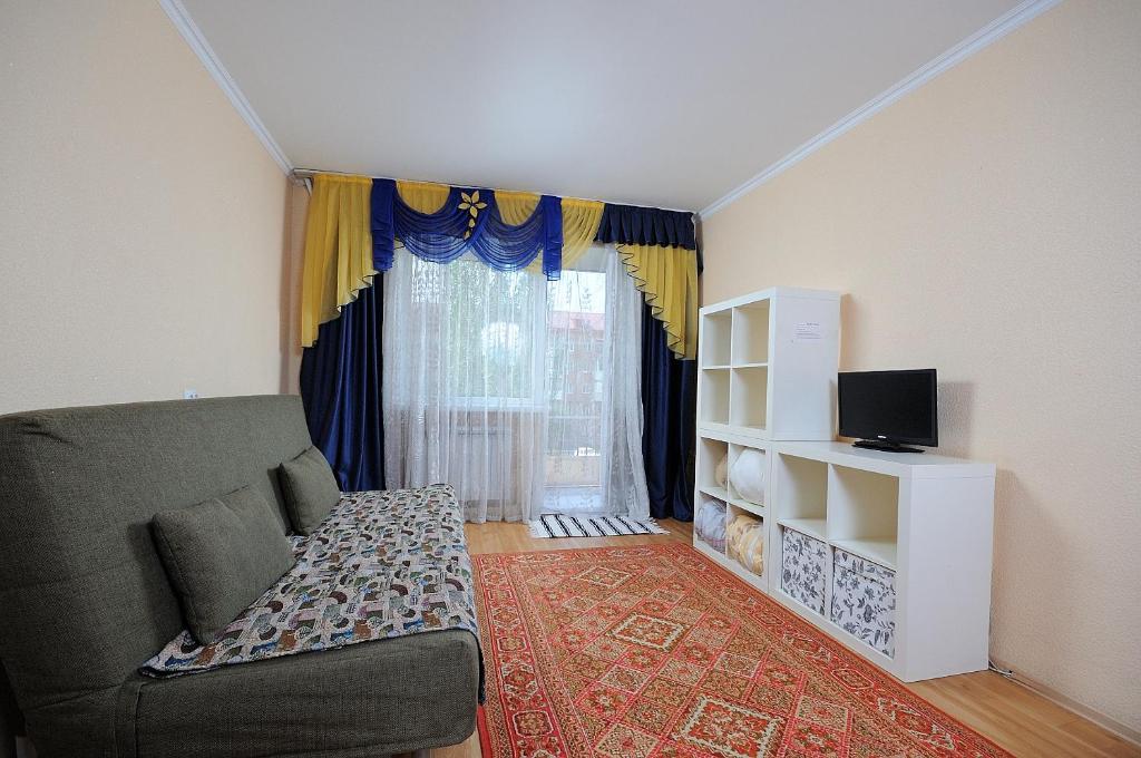 a living room with a couch and a window at Omsk Sutki Apartments on Mira 10 in Omsk