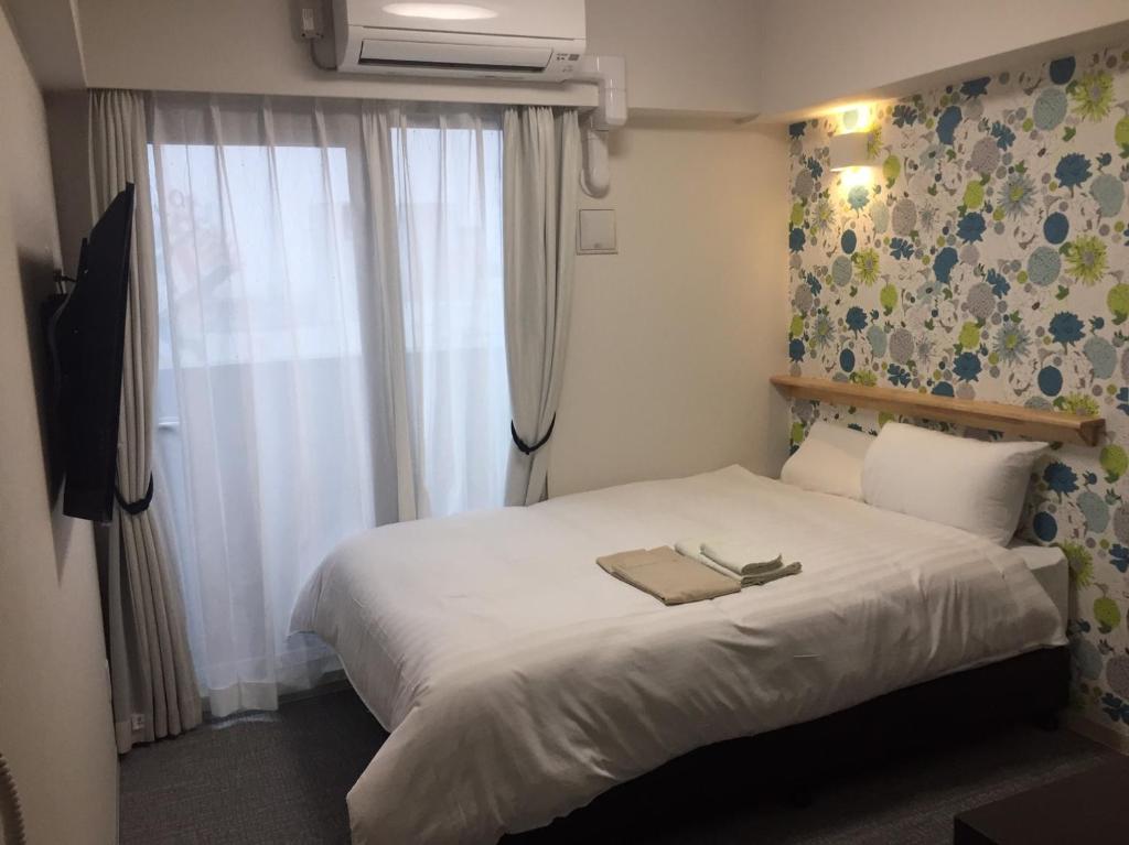 a bedroom with a white bed with a window at Omura Station Hotel Nagasaki Airport in Omura