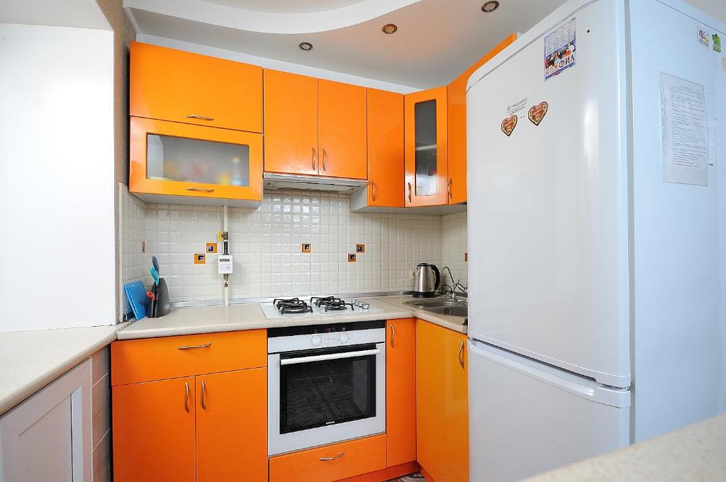 オムスクにあるКарла Маркса 31 Аのキッチン(オレンジ色のキャビネット、白い冷蔵庫付)
