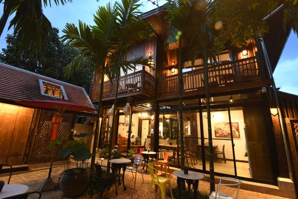 ein Gebäude mit einem Balkon sowie Tischen und Stühlen in der Unterkunft The Eight Ratvithi House in Chiang Mai