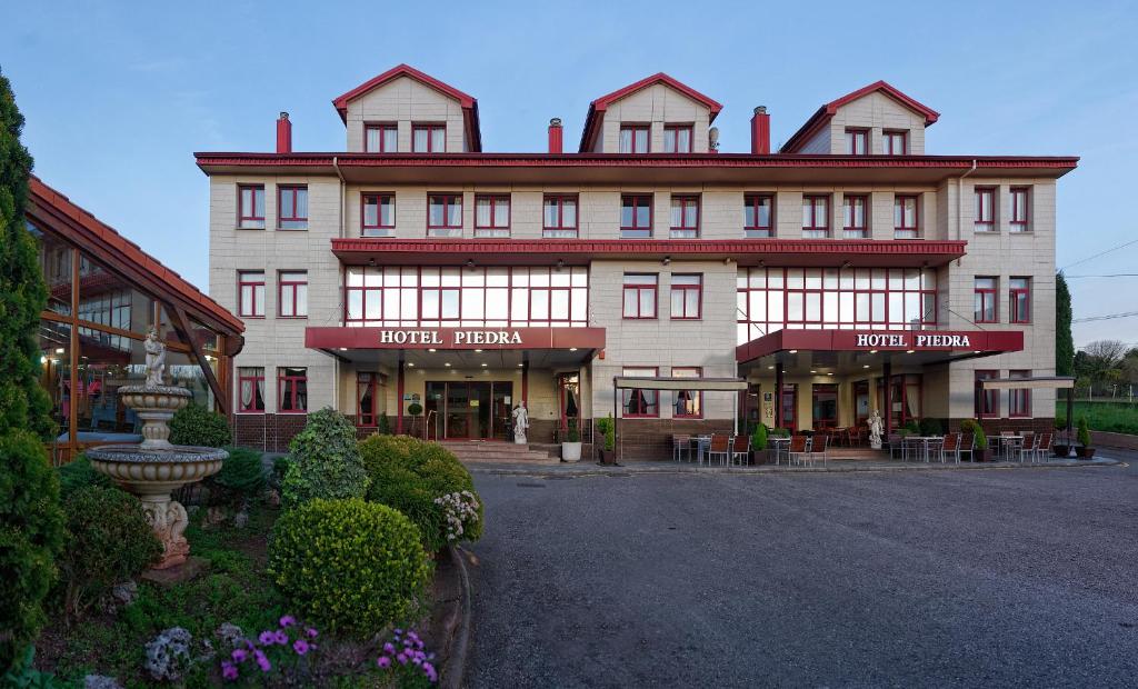 un grand bâtiment blanc avec un toit rouge dans l'établissement Hotel Piedra, à Perlora