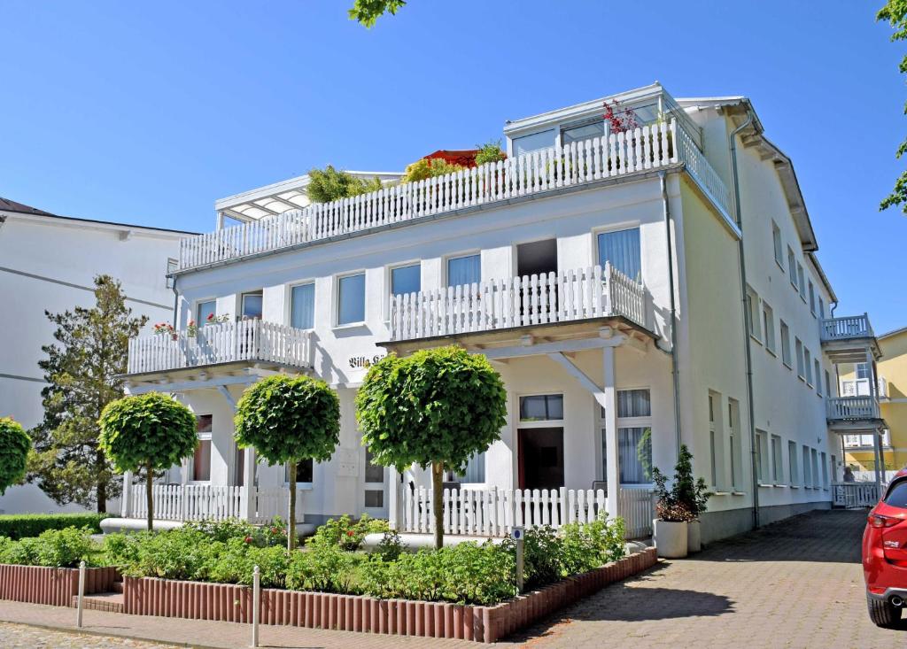a white building with a balcony and trees at Ferienappartement mit Ostseeblick in Göhren