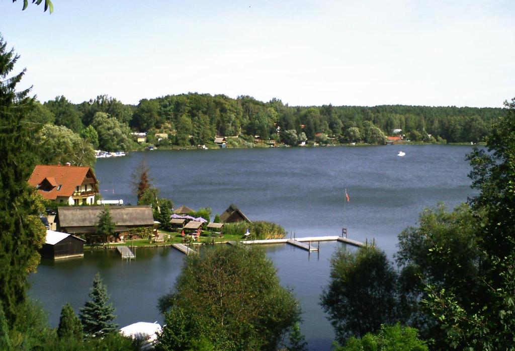 a view of a lake with a house and a dock at Pension Zechliner Hof in Flecken Zechlin