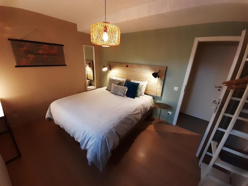 um quarto com uma cama branca e um lustre em Appartement rez Terrasse et Jardin em Huy
