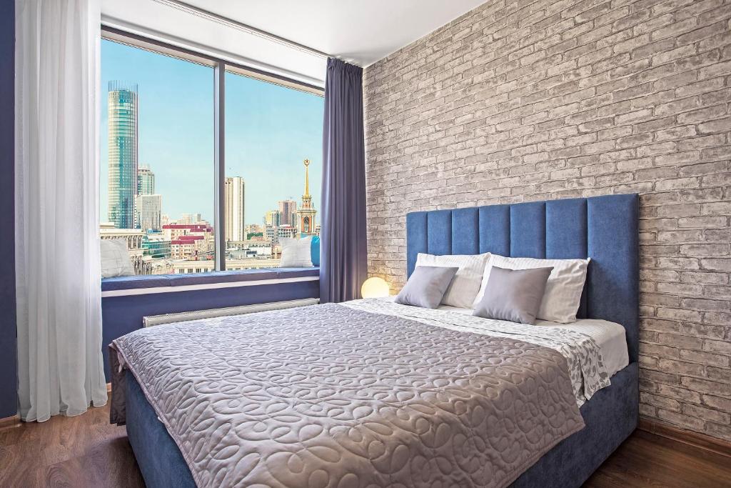 a bedroom with a blue bed with a brick wall at Apartments Home Hotel in Yekaterinburg