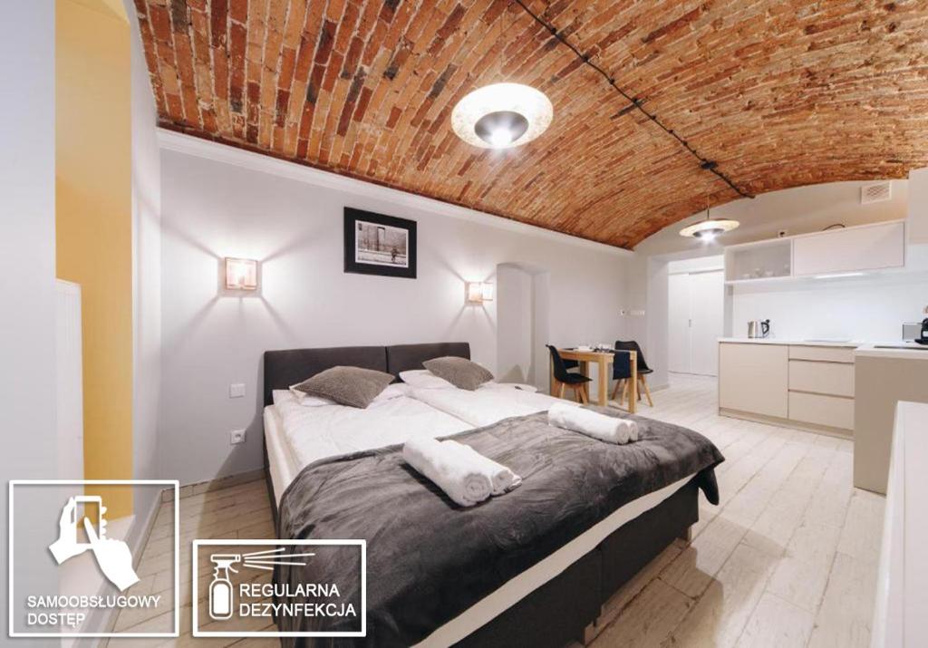 ein Schlafzimmer mit einem großen Bett und einer Holzdecke in der Unterkunft Platan Apartments - Ground Floor - Studencka 25 Street in Krakau