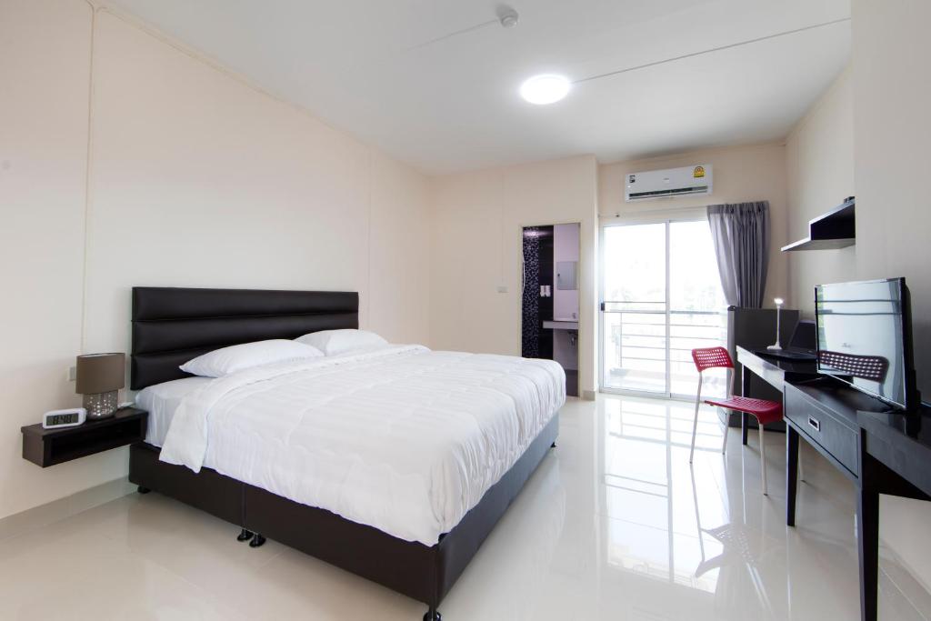 - une chambre avec un lit, un bureau et une télévision dans l'établissement JJ Residence, à Pluak Daeng