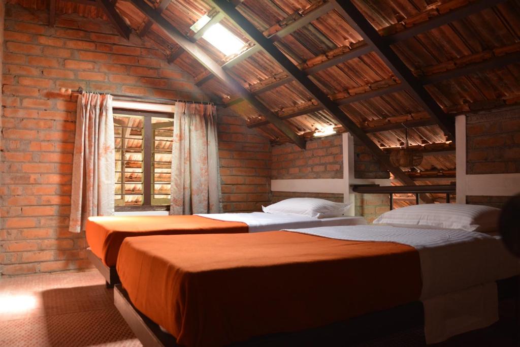 3 camas en una habitación con una pared de ladrillo en Annapara Home Stay en Vythiri
