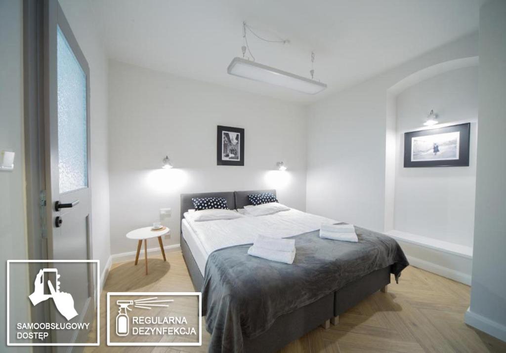 a white bedroom with a bed and a table at Platan Apartments-Unique -1 bedroom apartment in Krakow
