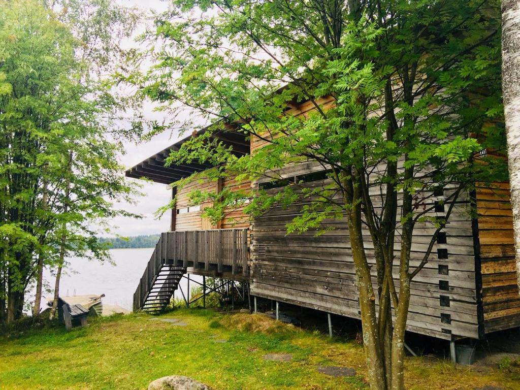 a wooden house with a staircase next to a lake at Kyly in Savonlinna