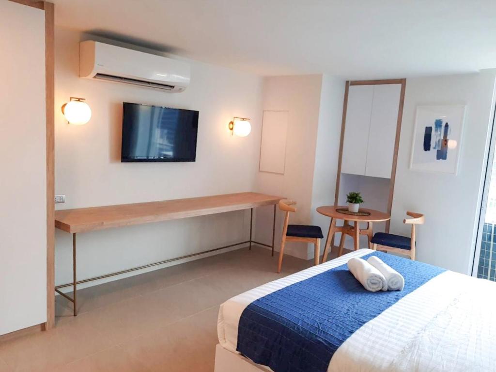 This closer room view focuses on the bed, television wall, narrow console, and small dining table.